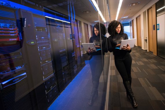 woman using MacBook near server room